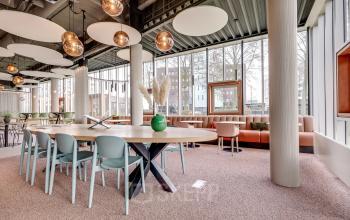 Stijlvolle kantoorruimte te huur op Maanlander 47 in Amersfoort Calveen, met een grote tafel en moderne verlichting, ideaal voor vergaderingen in een open en lichte omgeving.
