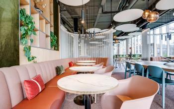 Stijlvolle kantoorruimte met ronde tafels, kleurrijke stoelen en planten in Maanlander 47, Amersfoort Calveen. Geschikt voor kantoorruimte huren met een moderne uitstraling en veel natuurlijk licht.