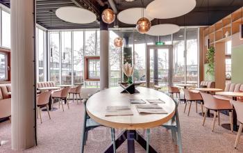 Moderne kantoorruimte met grote ovale tafel, lichte stoelen en decoratieve verlichting op Maanlander 47, Amersfoort Calveen. Ideaal voor vergaderingen of teamwork in een aantrekkelijk ingerichte werkomgeving.