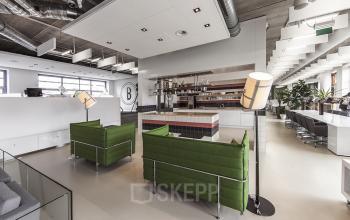 Moderne kantoorruimte met groene banken en een stijlvolle bar op Piet Mondriaanplein 13-31, ideaal voor huren bij Amersfoort Centraal Station.