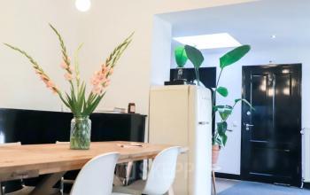 Veelzijdige kantoorruimte te huur aan Utrechtseweg 129, Amersfoort Centraal Station, met een modern ingerichte werkplek inclusief gepolijste houten tafel, designstoelen en decoratieve planten.