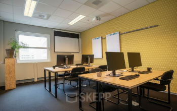 Moderne kantoorruimte in Amersfoort Centraal Station met drie bureaus, computers en een projector, ideaal voor werk of vergaderingen. Geschikt voor wie een kantoorpand wil huren op een centrale locatie.