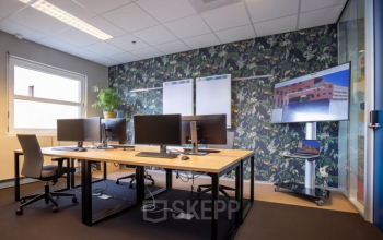 Gezellige kantoorruimte met moderne werkplekken, voorzien van beeldschermen en een inspirerende wand met plantenprint. Ideale locatie voor kantoorruimte huren in Amersfoort Centraal Station.