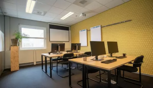 Moderne kantoorruimte in Amersfoort Centraal Station met drie bureaus, computers en een projector, ideaal voor werk of vergaderingen. Geschikt voor wie een kantoorpand wil huren op een centrale locatie.