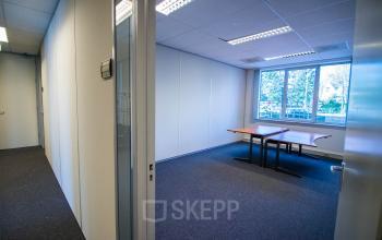 Lege kantoorruimte te huur aan Stadsring 157-165 in Amersfoort Centrum, met een groot raam en een paar tafels tegen een lichte muur.