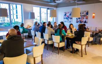 Kantoorruimte huren in Amersfoort Centrum met mensen die lunchen aan tafels in een gemeubileerde ruimte.