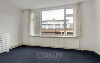 Lichte kantoorruimte met groot raam en zicht op gebouwen in Amersfoort Centrum, geschikt om te huren als werkplek. De ruimte oogt modern en functioneel.
