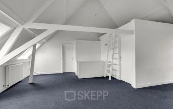 Lichte, open kantoorruimte te huur op Stadsring 248-250, Amersfoort, met grijze vloerbedekking en witte schuine plafonds. Ruimte is blanco en biedt mogelijkheden voor eigen inrichting.