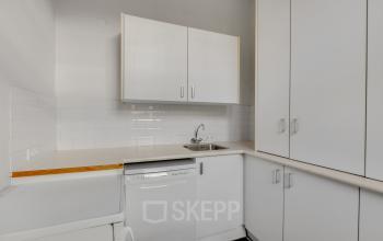 Functional pantry area in office at Stadsring 248-250, Amersfoort Centrum, featuring built-in white cabinets and a dishwasher, ideal for a practical office environment.