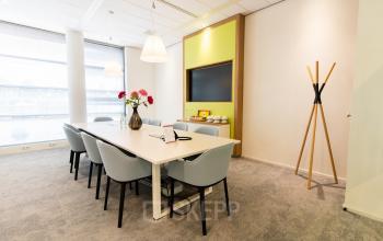 Vergaderzaal van een kantoorpand aan Databankweg 26, Amersfoort De Hoef, voorzien van een lange witte tafel met stoelen, een scherm aan de muur, en decoratieve elementen.