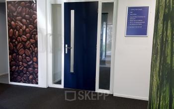 Ingang van een kantoorpand op Algolweg 9-11, Amersfoort De Hoef. Neutraal interieur met opvallende muurfoto's van koffiebonen en gras. Ideaal voor het huren van moderne kantoorruimte.