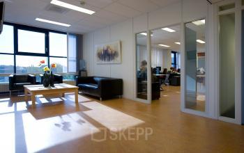 Ruime kantoorpand op Algolweg 9-11, Amersfoort De Hoef, met gemeubileerde werkplekken en een lichte, open indeling. Werknemers voeren kantooractiviteiten uit aan de tafels. Ideaal voor kantoorruimte huren.