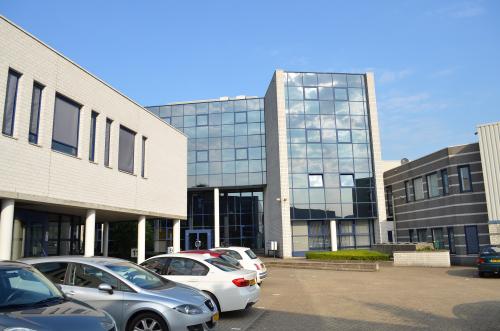 De voorzijde van een modern kantoorpand met glasgevels, gelegen aan de Algolweg 9-11 in Amersfoort De Hoef, met meerdere geparkeerde auto's zichtbaar op de voorgrond.