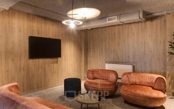 Gezellige lounge met comfortabele zitruimte, houten wandpanelen en moderne verlichting in kantoorpand aan Vanadiumweg 11, Amersfoort Isselt. Ideaal om even te ontspannen tijdens het kantoorwerk.