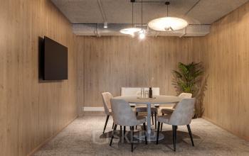 Stijlvolle vergaderruimte aan Vanadiumweg 11 in Amersfoort Isselt, met houten wanden, tafel, stoelen en een plant. Ideaal voor bedrijven die een functionele kantoorruimte willen huren.