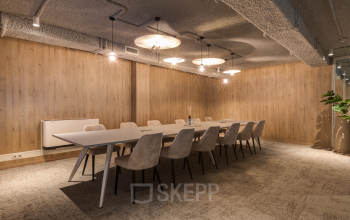 Vergaderzaal in het kantoorpand aan Vanadiumweg 11, Amersfoort Isselt, voorzien van lange tafel en moderne stoelen, lichte houten wanden en sfeerverlichting, ideaal voor zakelijke besprekingen en kantoorruimte huren.
