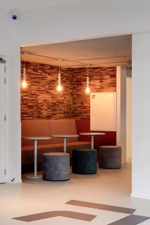 Gezellige kantoorrustplek met stijlvolle stenen wand, moderne verlichting, en comfortabele zitmogelijkheden in een kantoorpand aan de Vanadiumweg 11, Amersfoort Isselt.