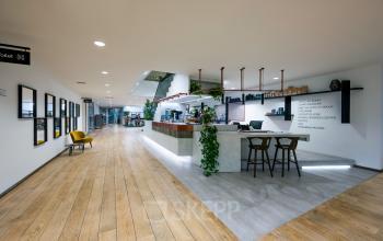 Moderne kantoorruimte te huur op De Gondel 1 in Amstelveen met een stijlvolle receptie, houten vloer en veel groen. Ideaal voor zakelijke doeleinden.