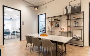 Kantoorruimte te huur op H.J.E. Wenckebachweg 123 in Amsterdam Amstel Business Park. Moderne, gemeubileerde vergaderruimte met design elementen en een grote tafel met stoelen.