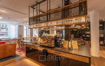 Gezellige kantoorruimte op Amstelvlietstraat 4, Amsterdam, met een stijlvolle pantry, comfortabele zitplaatsen en moderne koffiemachine, ideaal voor informele ontmoetingen en ontspanning.