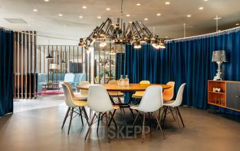 Kantoorruimte huren aan Amstelvlietstraat 4 in Amsterdam Amstel Business Park met stijlvolle inrichting, ronde tafel, design stoelen, moderne verlichting en blauwe gordijnen.