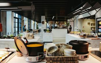 Moderne kantoorpand op Joan Muyskenweg 137 in Amsterdam Amstel Business Park met lichte, gemeubileerde werkruimtes en kantine waar personen bezig zijn met lunchvoorbereiding.