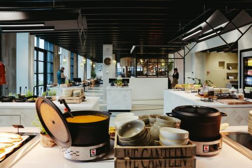 Moderne kantoorpand op Joan Muyskenweg 137 in Amsterdam Amstel Business Park met lichte, gemeubileerde werkruimtes en kantine waar personen bezig zijn met lunchvoorbereiding.