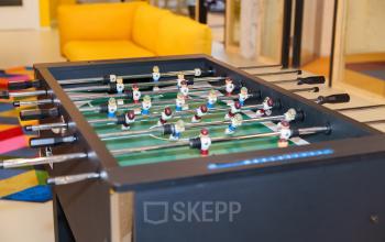 Kantoorruimte huren met tafelvoetbaltafel in Amsterdam Amstel Business Park, gelegen aan Willem Fenengastraat 2, met een gele bank en kleurrijke tapijten op de achtergrond.
