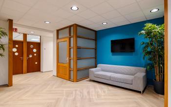 Modern kantoor met een blauwe accentmuur en grijze bank in Amsterdam Amstel Business Park op Joan Muyskenweg 82, ideaal voor kantoorruimte huren.