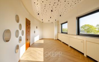 Foto van een modern, licht interieur van een kantoorpand op Joan Muyskenweg 82, Amsterdam. De ruimte heeft houten vloeren en een uniek plafondontwerp. Ideaal voor kantoorruimte huren in Amsterdam Amstel Business Park.