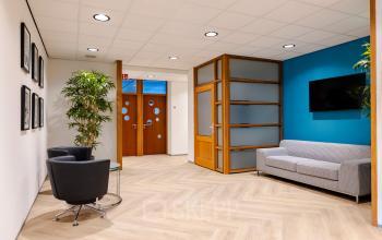 Ontvangstruimte in kantoorpand aan Joan Muyskenweg 82, met moderne meubels, een zitgedeelte en planten, ideaal voor een zakelijke bijeenkomst in Amsterdam Amstel Business Park.