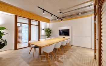 Vergaderruimte in een modern kantoorpand aan Joan Muyskenweg 82, Amsterdam Amstel Business Park, met houten tafel, stoelen en tv voor zakelijke bijeenkomsten. Ideaal voor bedrijven die kantoorruimte willen huren.