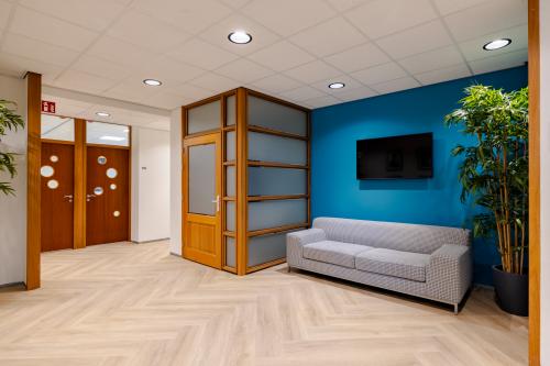 Modern kantoor met een blauwe accentmuur en grijze bank in Amsterdam Amstel Business Park op Joan Muyskenweg 82, ideaal voor kantoorruimte huren.