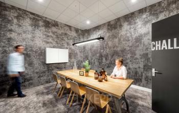 Kantoorruimte huren aan Joan Muyskenweg 22 in Amsterdam Amstel Business Park. Twee mensen in een vergaderruimte met industriële stijl en houten tafel.