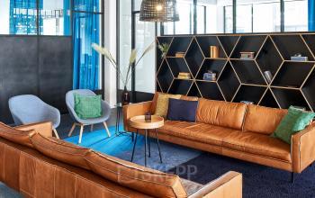Loungegedeelte in kantoorpand Joan Muyskenweg 22, Amsterdam Amstel Business Park, met leren banken, designmeubels en decoratieve elementen.