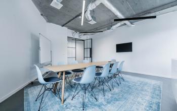 Moderne kantoorruimte met een lange tafel en blauwe stoelen op H.J.E. Wenckebachweg 90-108, geschikt voor vergaderingen of teamwork in Amsterdam Amstel Business Park.