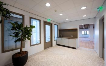 Ingang van een kantoorpand op Joop Geesinkweg 601 in Amsterdam Amstel Business Park, met plantenbak, pantry en lichte inrichting. Huur kantoorruimte in moderne omgeving.