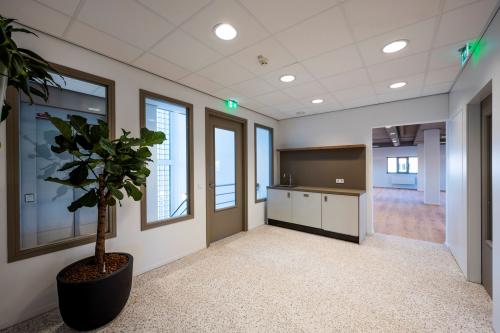 Ingang van een kantoorpand op Joop Geesinkweg 601 in Amsterdam Amstel Business Park, met plantenbak, pantry en lichte inrichting. Huur kantoorruimte in moderne omgeving.