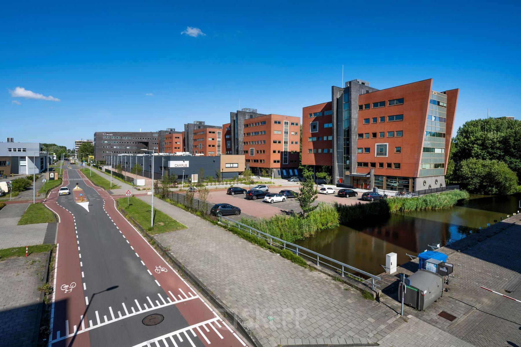 Kantoorpand aan Joop Geesinkweg 601, Amsterdam Amstel Business Park, gezien vanaf de straat met auto’s geparkeerd op het terrein.