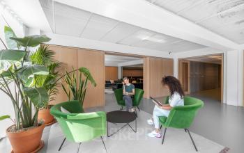 Heldere kantoorruimte op Mr. Treublaan 7 in Amsterdam Amstel met groene stoelen en planten, personen in gesprek.