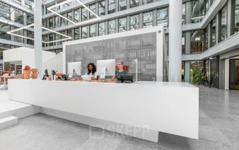 Modern kantoor met twee personen achter een witte balie in het kantoorpand aan Mr. Treublaan 7, Amsterdam Amstel.