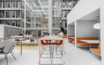 Moderne werkplekken in kantoorpand aan Mr. Treublaan 7, Amsterdam Amstel, met collega's in overleg bij een lange tafel.