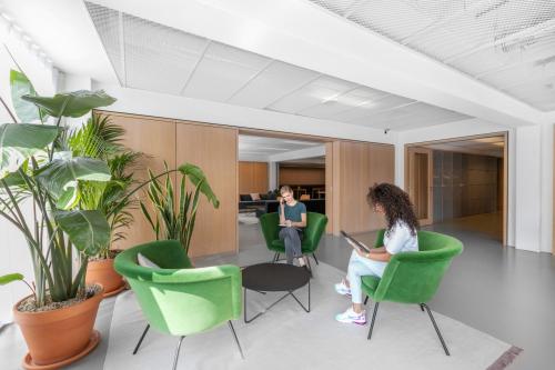 Heldere kantoorruimte op Mr. Treublaan 7 in Amsterdam Amstel met groene stoelen en planten, personen in gesprek.