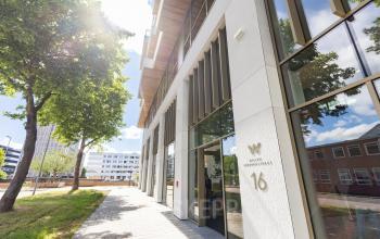 Buitenzijde van het kantoorpand aan de Willem Fenengastraat 16 in Amsterdam Amstel, ideaal voor het huren van kantoorruimte. Het moderne gebouw omgeven door groen straalt professionaliteit uit.