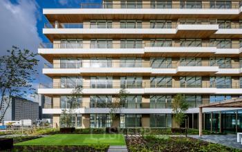 Buitenzijde van een modern kantoorpand op Willem Fenengastraat 16, Amsterdam Amstel. Strakke architectuur met houten accenten en veel glas. Geschikt voor bedrijven die kantoorruimte willen huren.