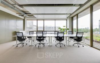 Heldere kantoorruimte met grote ramen en ergonomische bureaustoelen in Amsterdam Amstel, geschikt voor werk en vergaderingen.