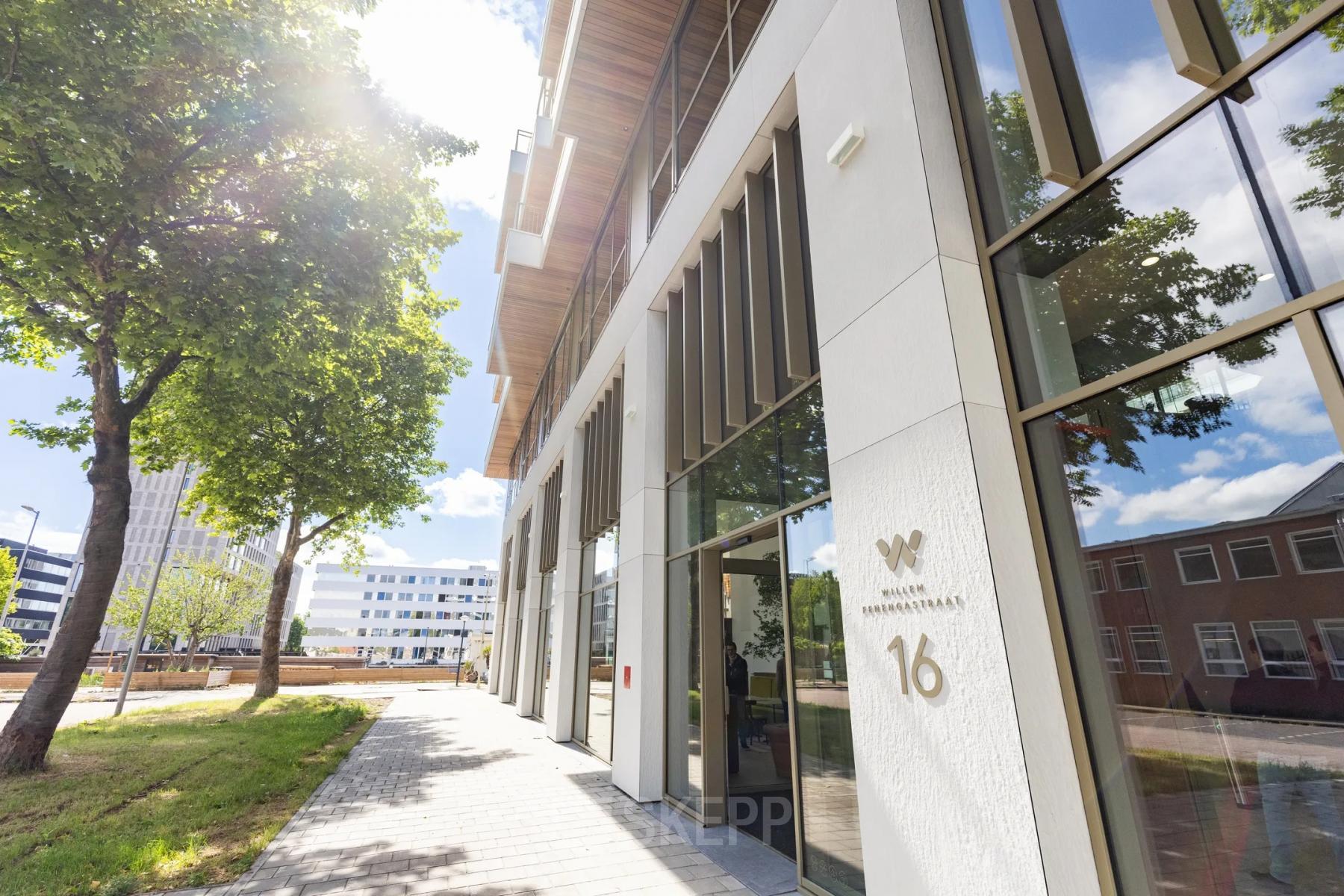 Buitenzijde van het kantoorpand aan de Willem Fenengastraat 16 in Amsterdam Amstel, ideaal voor het huren van kantoorruimte. Het moderne gebouw omgeven door groen straalt professionaliteit uit.