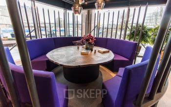 Moderne vergaderruimte met paarse, ronde zitbanken en een decoratieve tafel in een kantoorpand op Prins Bernhardplein 200, ideaal voor kantoorruimte huren in Amsterdam Amstel.