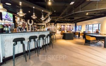 Ruime en moderne kantoorruimte op Prins Bernhardplein 200 in Amsterdam Amstel met een stijlvolle bar, comfortabele zitplaatsen en veel natuurlijk licht, ideaal voor kantoorruimte huren.