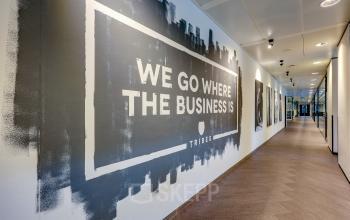 Gang in kantoorpand Prins Bernhardplein 200, Amsterdam Amstel met artistieke muurschildering en moderne verlichtingsarmaturen. Ideaal voor kantoorruimte huren in een dynamische omgeving.